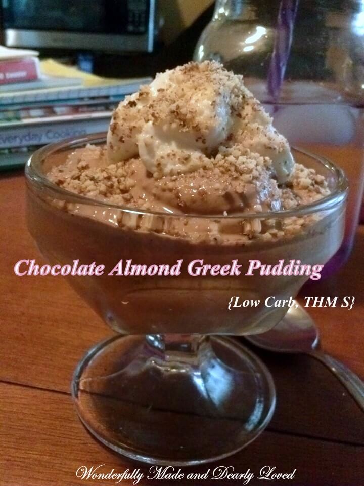 A creamy chocolate almond pudding made from greek yogurt and topped with ground almonds and whipped cream.